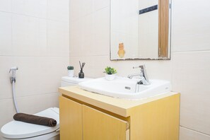 Une salle de bain avec un lavabo blanc, un miroir, des toilettes et une serviette.