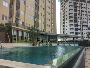 Une piscine dotée d’un espace de repos couvert, entourée d’immeubles résidentiels de grande hauteur.