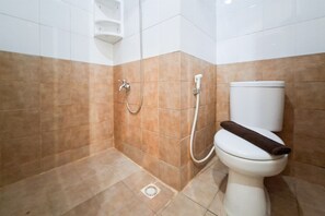 Ein Badezimmer mit Dusche, Toilette und einer weißen Ablage.
