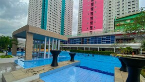 Zona de piscina con un edificio moderno al fondo.