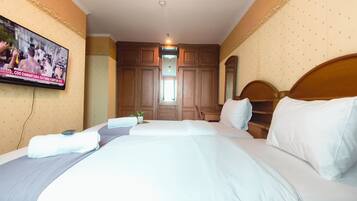 A hotel room with a large bed, a television mounted on the wall, and wooden furniture.