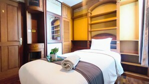 Ein Hotelzimmer mit Bett, Nachttisch, Blumentopf und einer eingebauten Regalanlage.