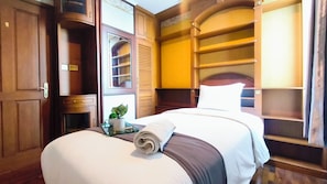 Ein Hotelzimmer mit Bett, Nachttisch, Blumentopf und einer eingebauten Regalanlage.