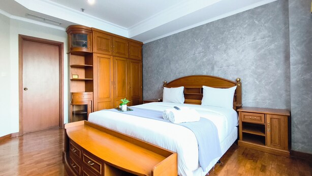 Ein Hotelzimmer mit einem hölzernen Bett, einem Nachttisch, einer Bank und eingebauten Holzschränken.