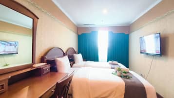 A hotel room with two beds, a desk, a TV, and a large mirror.