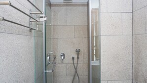 A modern shower with a glass door, a handheld showerhead, and a wall-mounted faucet. - Studio Bright Areum Residence At Antasari Place (Jakarta)