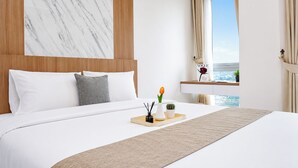 A hotel room with a large bed, a marble wall, a wooden headboard, a window with a view, and a bedside table with a vase of flowers. - Studio Bright Areum Residence At Antasari Place (Jakarta)