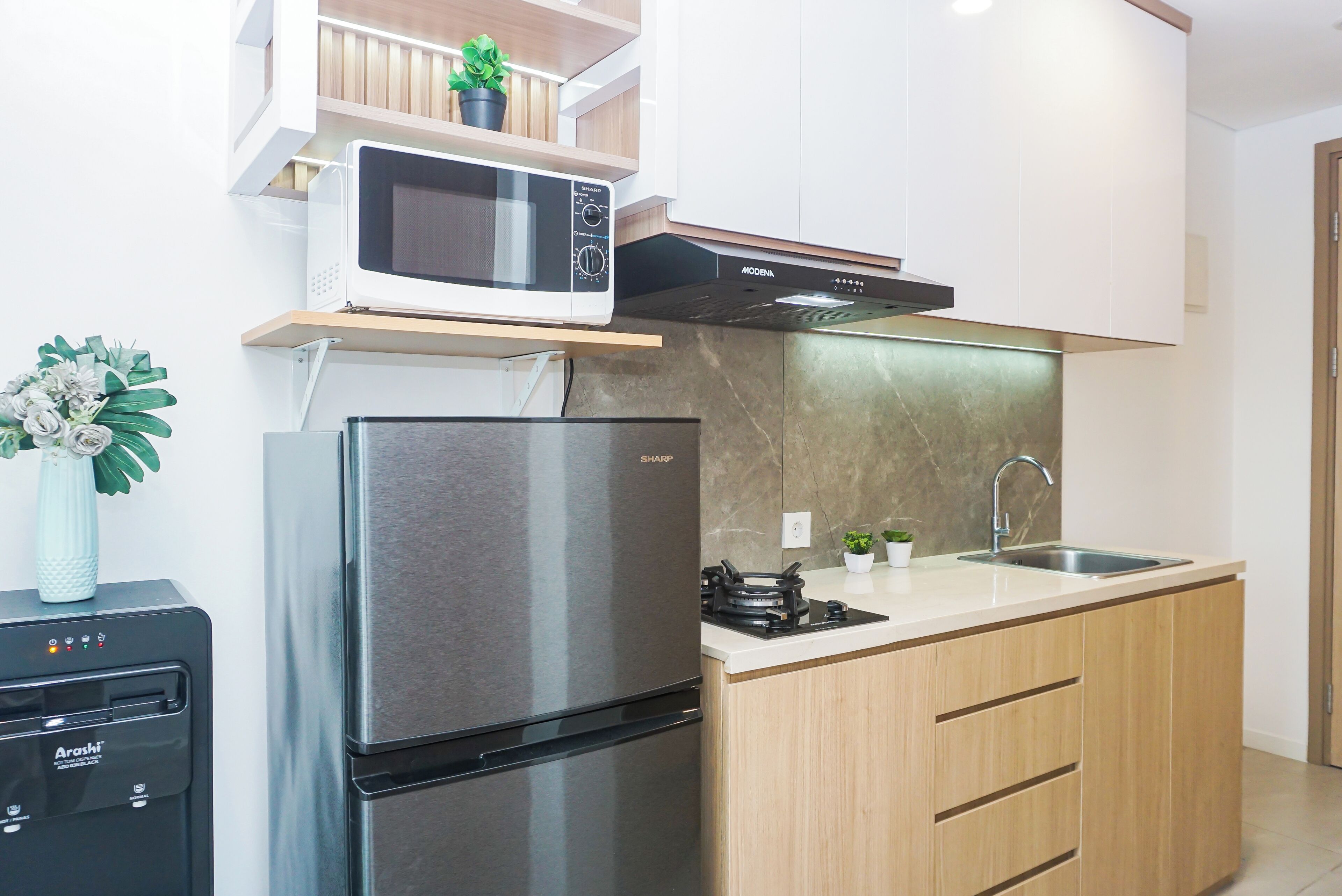 Una cocina moderna con refrigerador de acero inoxidable, microondas y estufa a gas.