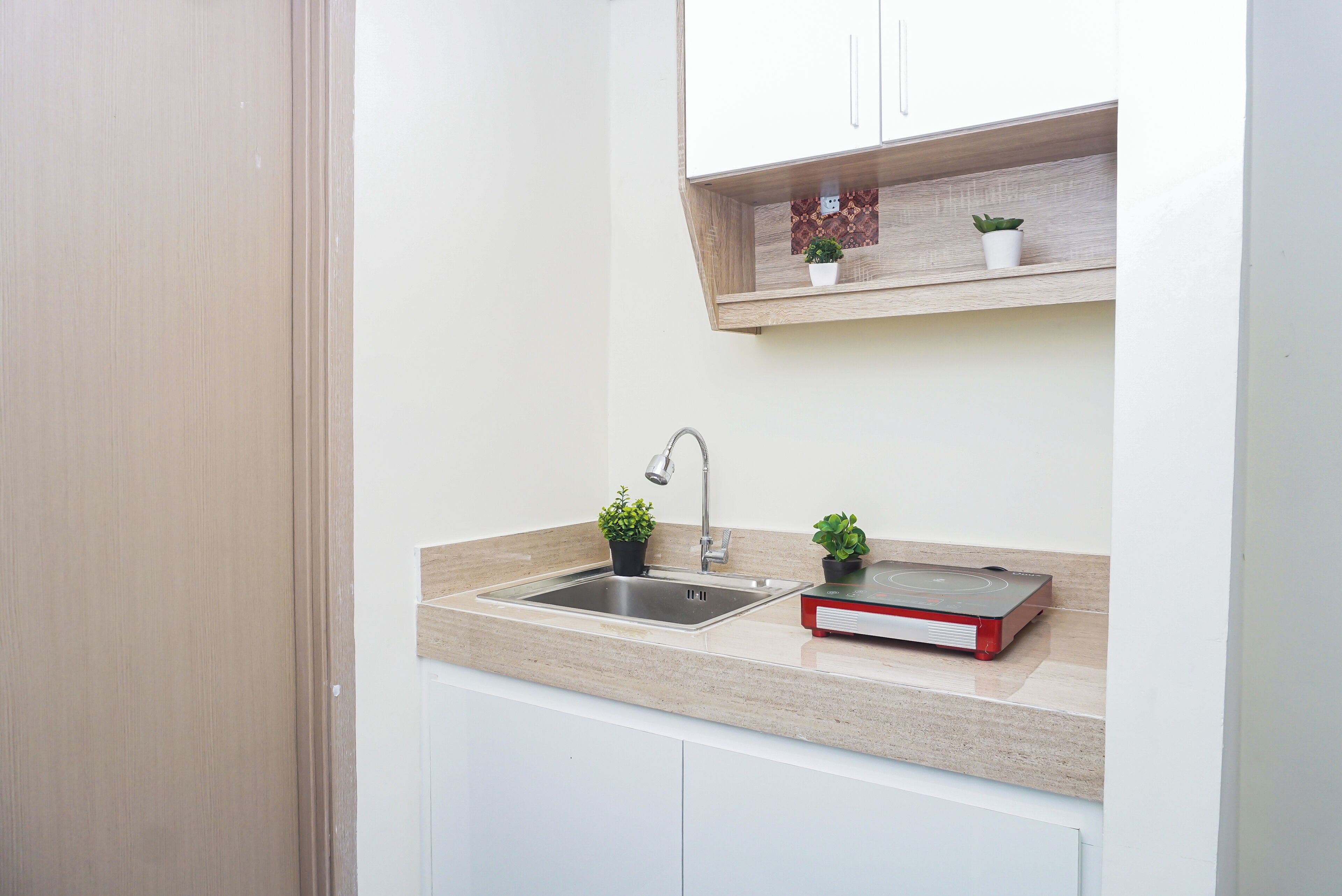 A kitchen with a stainless steel sink, a built-in stove, and two potted plants on the countertop.