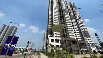Un edificio alto con varios pisos, cielo despejado y una calle con sendero para peatones.