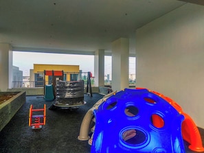 A play area with a slide, climbing structure, and a blue and orange ball pit. - Trendy 2Br At Apartment Vasanta Innopark (Cikarang)