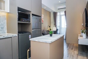 A modern kitchen with a built-in refrigerator, microwave, and oven. There's a small island with a potted plant. - Trendy 2Br At Apartment Vasanta Innopark (Cikarang)