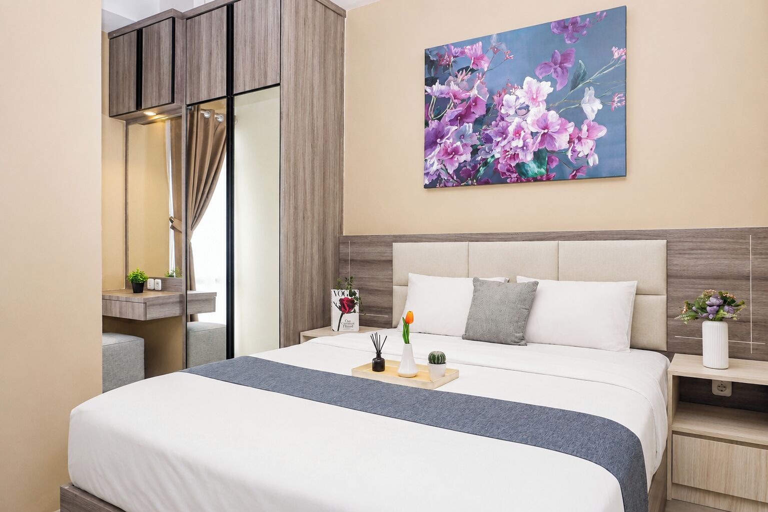 Una habitación de hotel moderna con una cama grande, una mesita de noche con un jarrón de flores, una lámpara de noche y un cuadro en la pared.