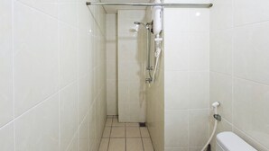 Kapea kylpyhuone, jossa on valkoiset laatat, käsisuihkulla varustettu suihku ja wc.