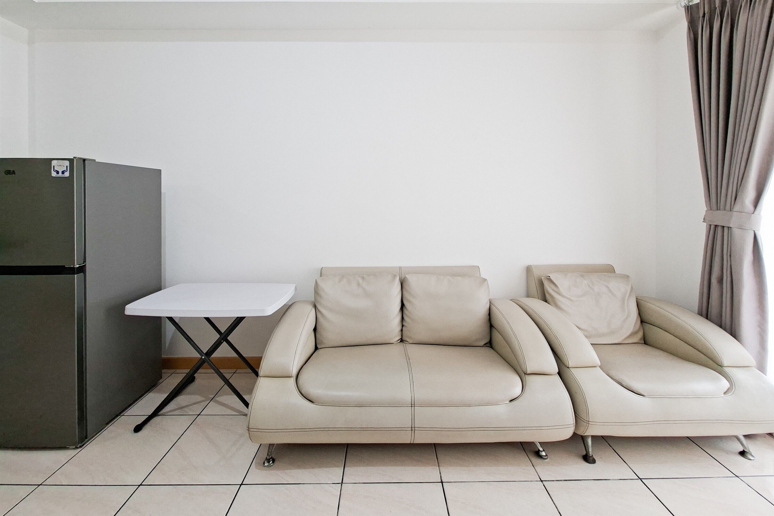 Ein Zimmer mit einer Couch, einem kleinen Tisch und einem Kühlschrank.