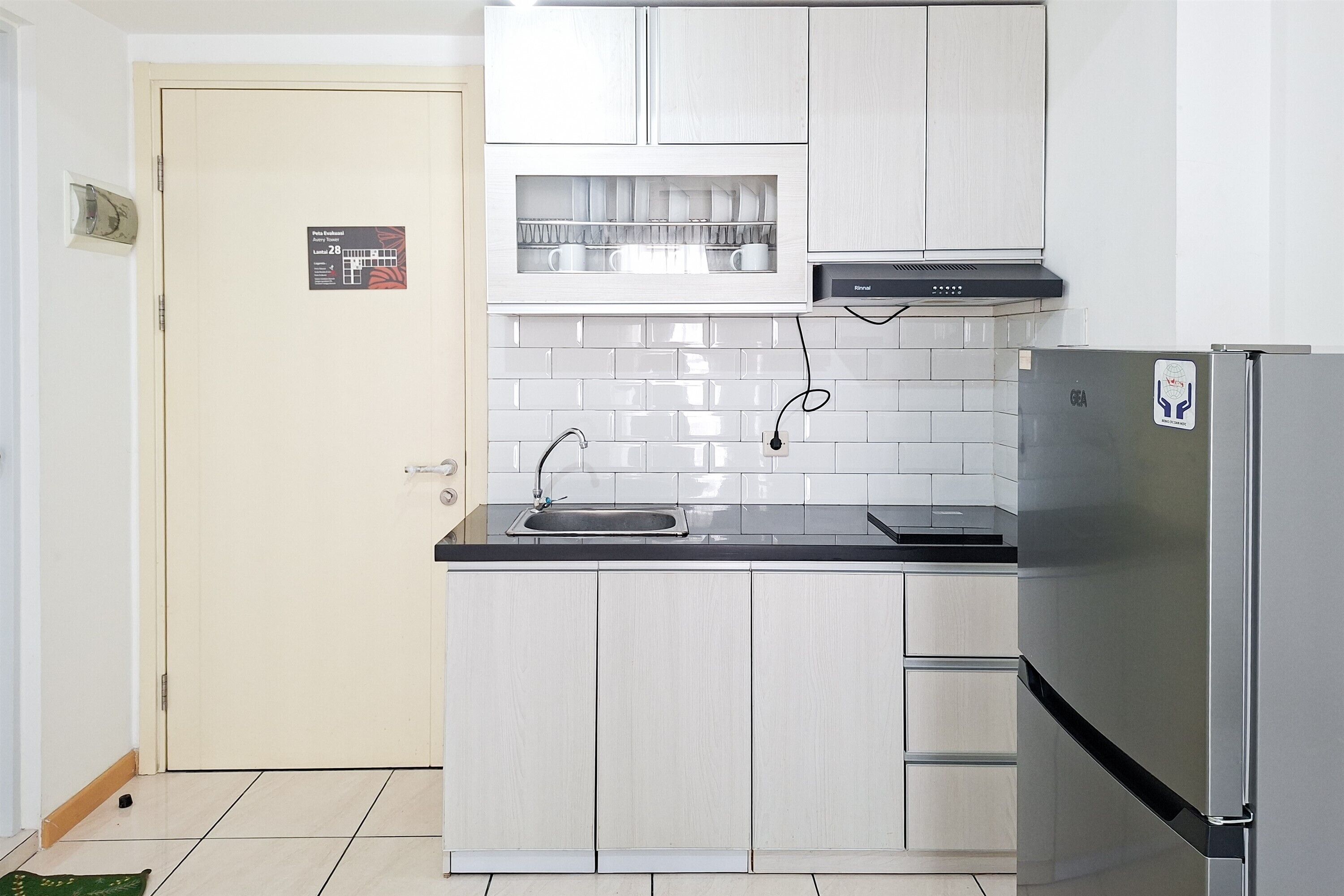 Eine kleine Küche mit einem Edelstahl-Kühlschrank, einer Spüle und einem eingebauten Backofen.