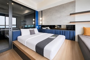 Una habitación de hotel moderna con una cama grande, una puerta de vidrio que da a un balcón y un tocador empotrado con luces.