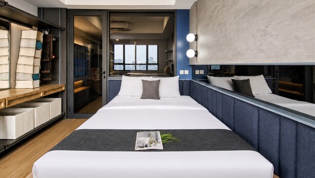 A modern hotel room with a large bed, bedside tables, a wardrobe, and a view of the city through the window. - Fully Furnished 1Br At Apartment Collins Boulevard (Tangerang)