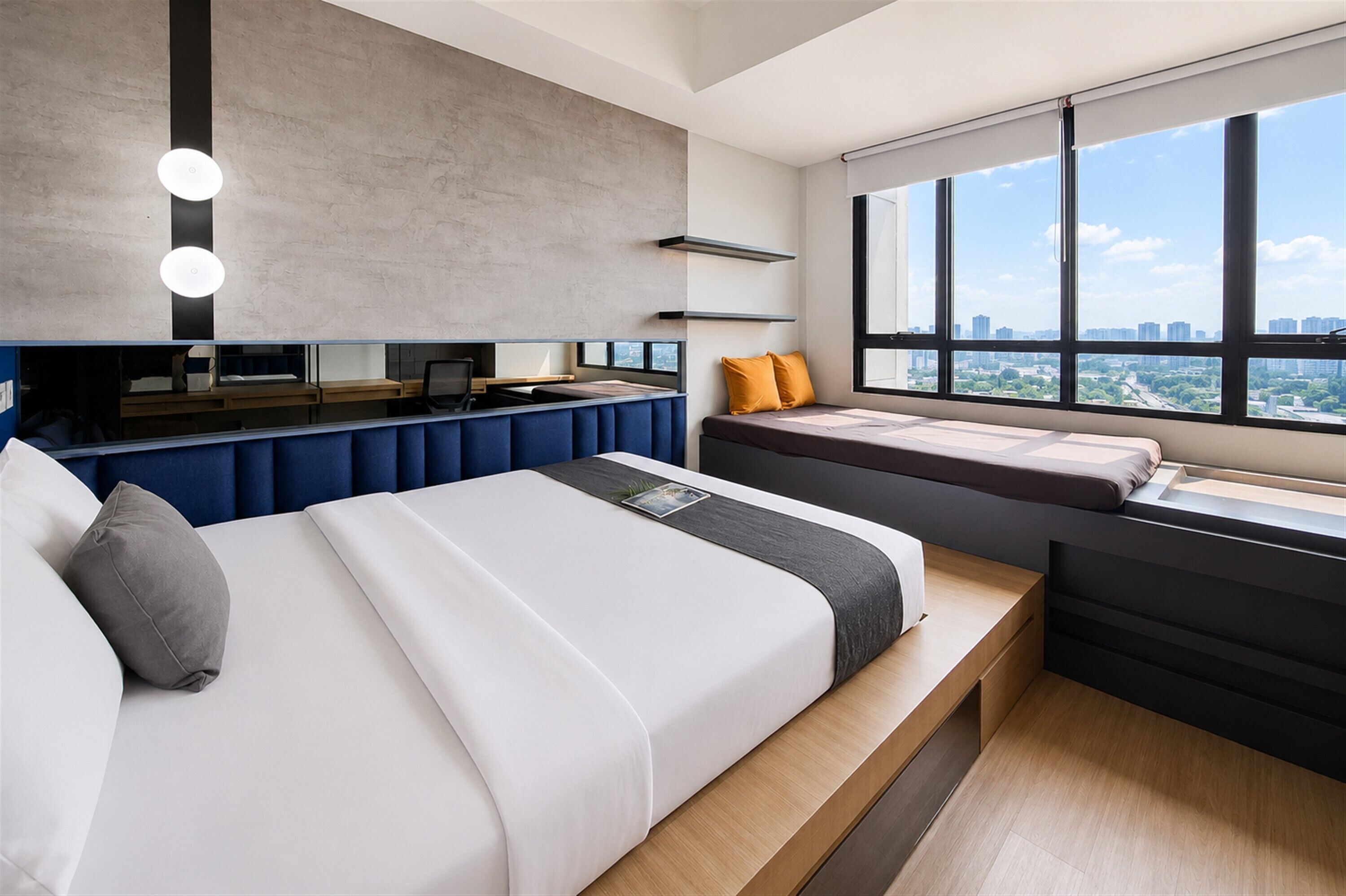 A modern bedroom with a large bed, a desk, and a view of the city through large windows.