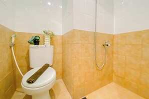 Casa de banho com sanita, chuveiro e lavatório.