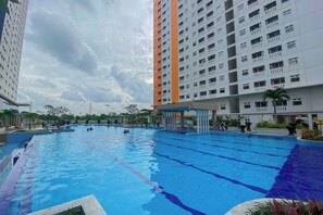 Piscina rodeada por edifícios altos, com céu claro acima.