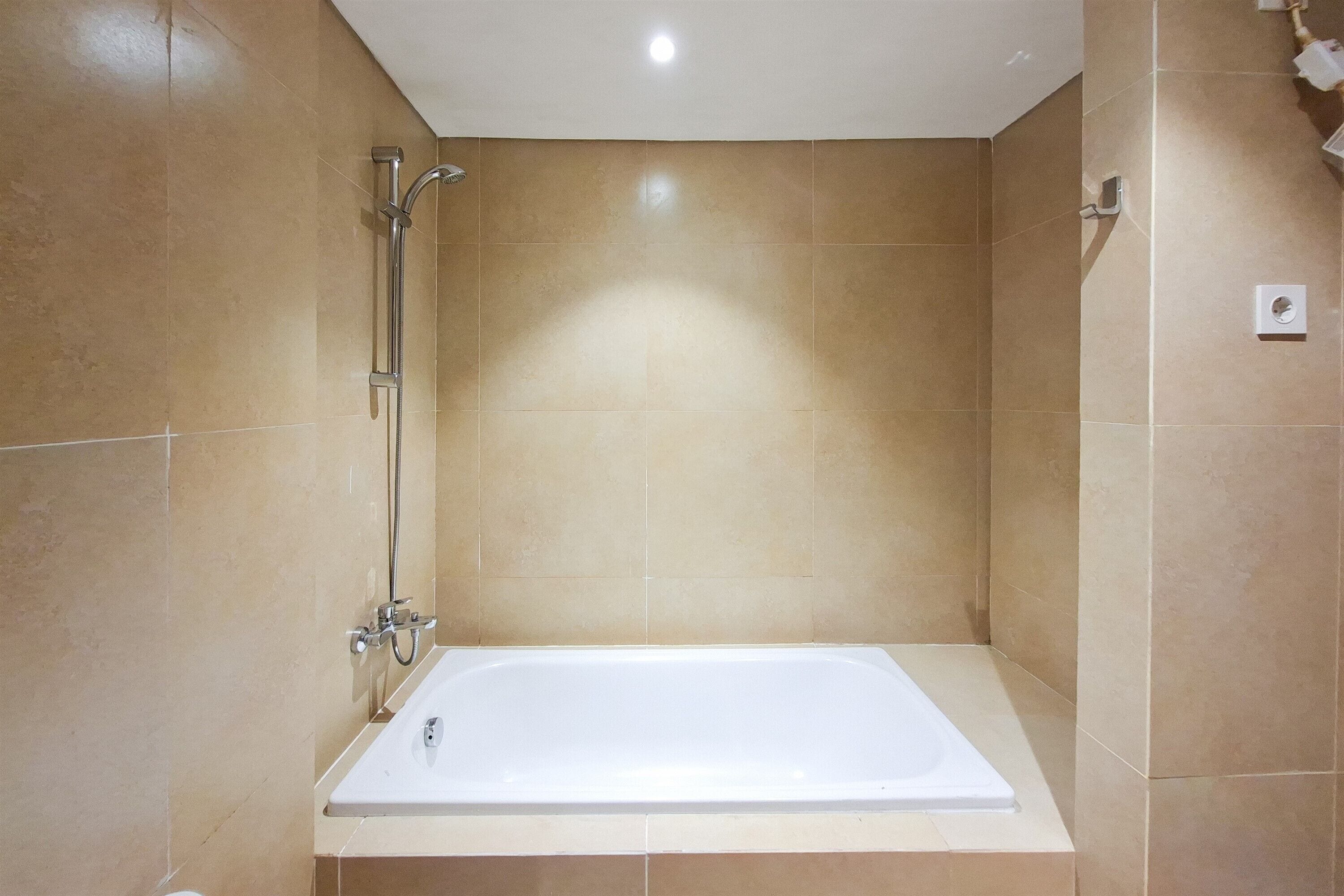 Un baño con bañera, ducha y una lámpara de pared.