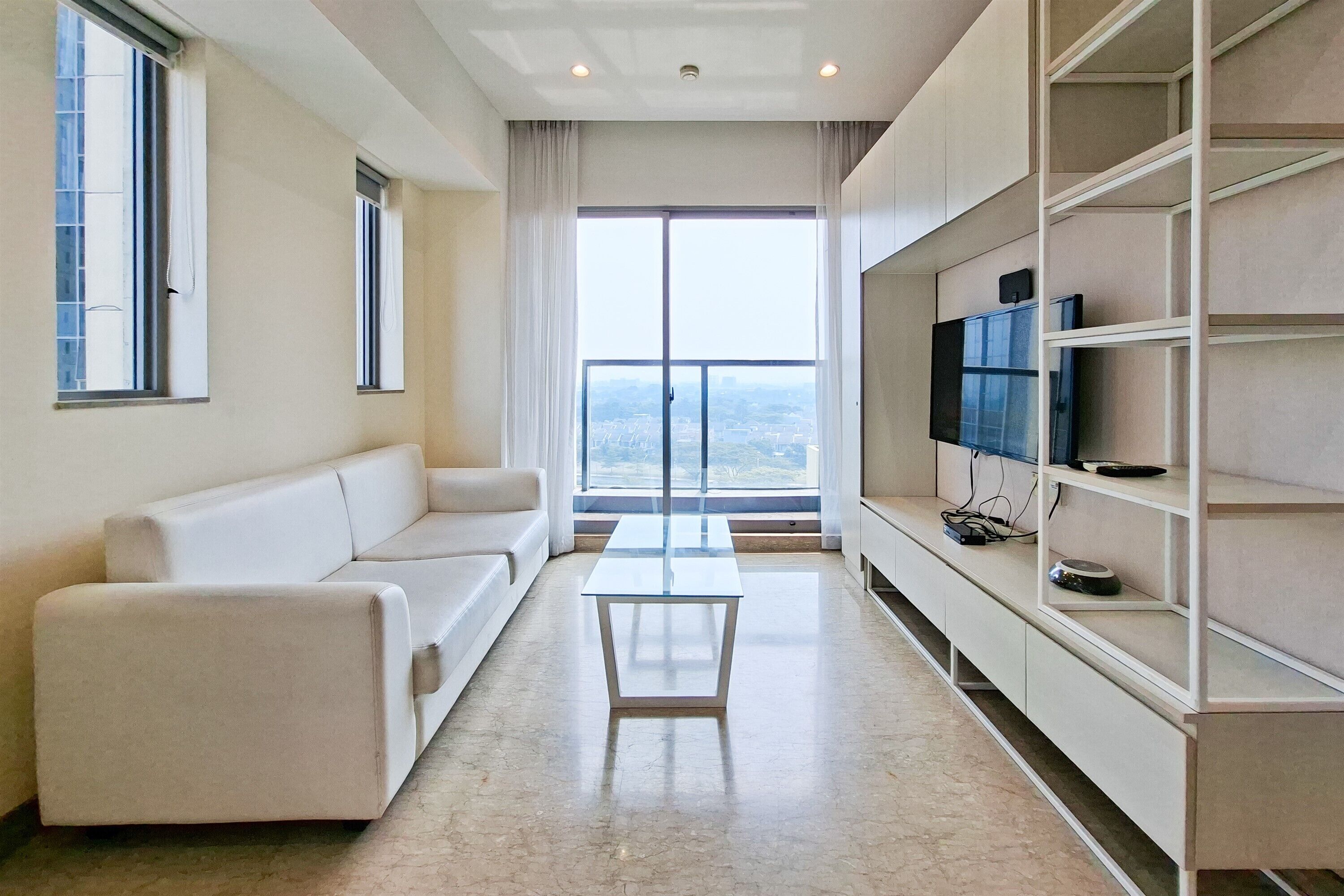 Una sala moderna con un sofá, una mesita de centro y un televisor sobre una estantería.
