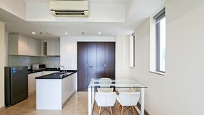 A modern kitchen with a central island, white cabinets, and a dark wood door. - Warm Space 2Br At Apartment Branz Bsd City (Tangerang)