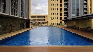 A swimming pool surrounded by modern buildings with a clear sky. - Warm Space 2Br At Apartment Branz Bsd City (Tangerang)