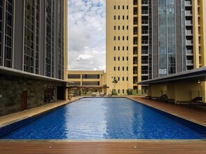 A swimming pool surrounded by modern buildings with a clear sky. - Warm Space 2Br At Apartment Branz Bsd City (Tangerang)