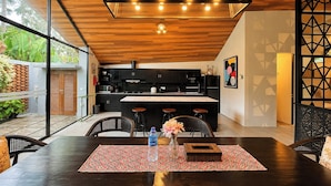 A modern kitchen with a wooden ceiling, black cabinets, and a central island with bar stools. - Tropical Paradise 3Br At Villa Coco (Nusa Dua)