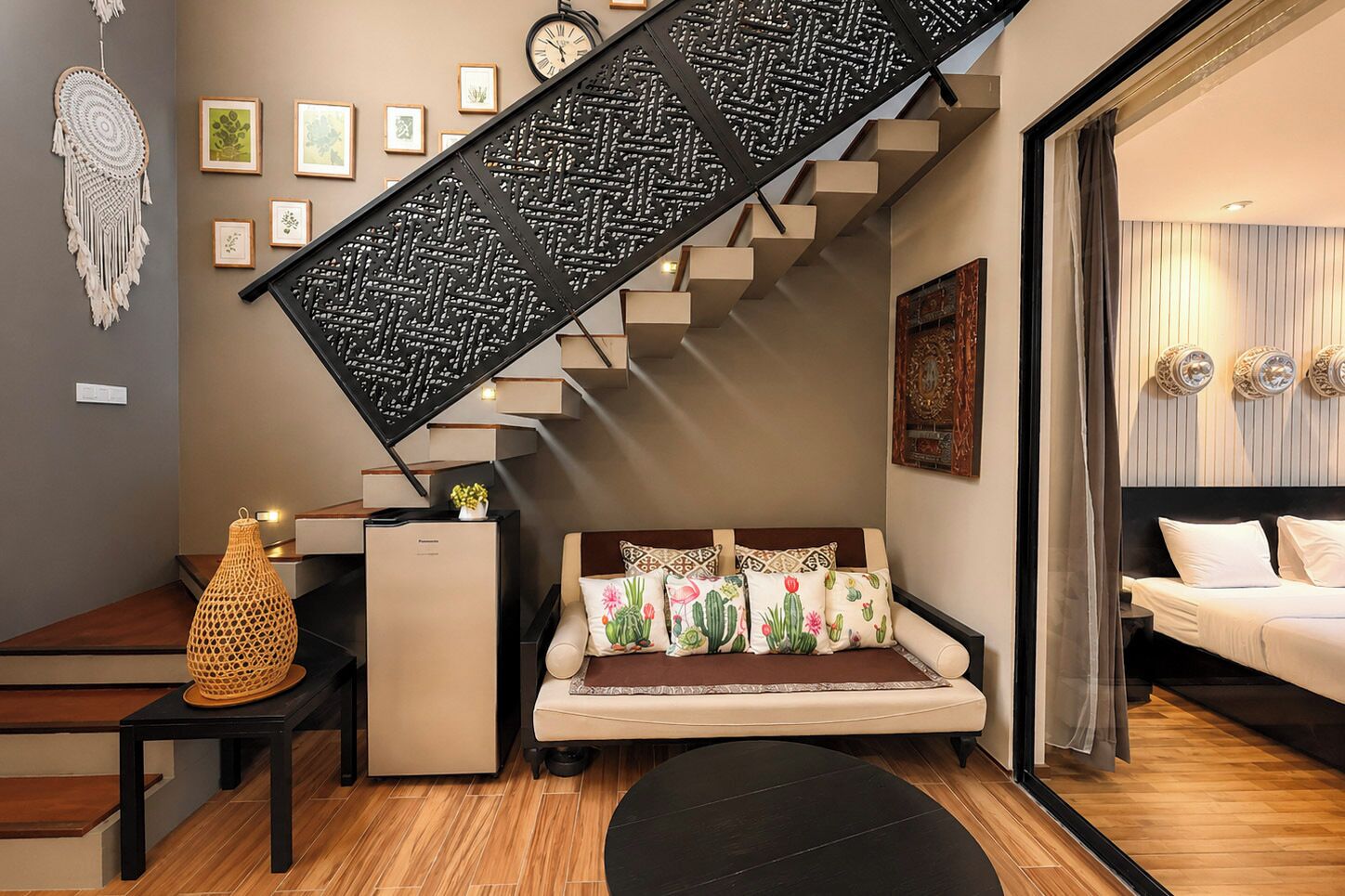 Ein modernes Wohnzimmer mit Treppe, einer Couch mit Kissen mit Kaktusmuster, einer dekorativen Laterne und Wandbildern.