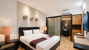 A hotel room with a large bed, two bedside tables, a TV, and a bathroom visible through an open door. - Tropical Paradise 3Br At Villa Coco (Nusa Dua)