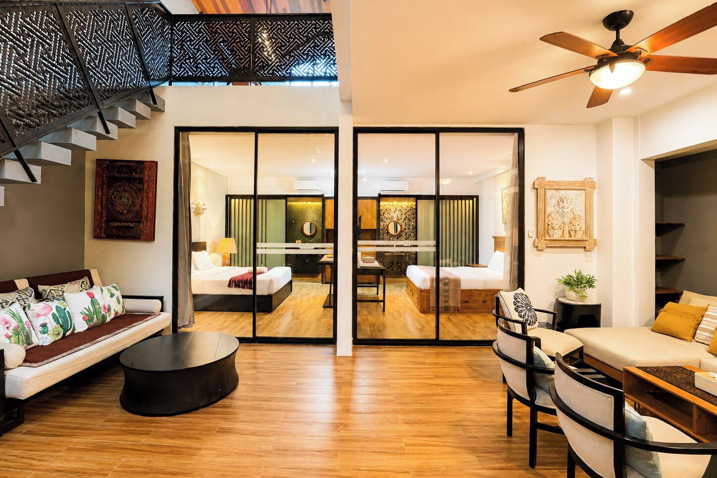 Ein modernes Interieur mit einer Couch, einem Essbereich, einem Deckenventilator und einer Treppe.