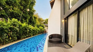 A swimming pool with blue and purple tiles, surrounded by lush greenery and modern outdoor furniture. - Tropical Paradise 3Br At Villa Coco (Nusa Dua)