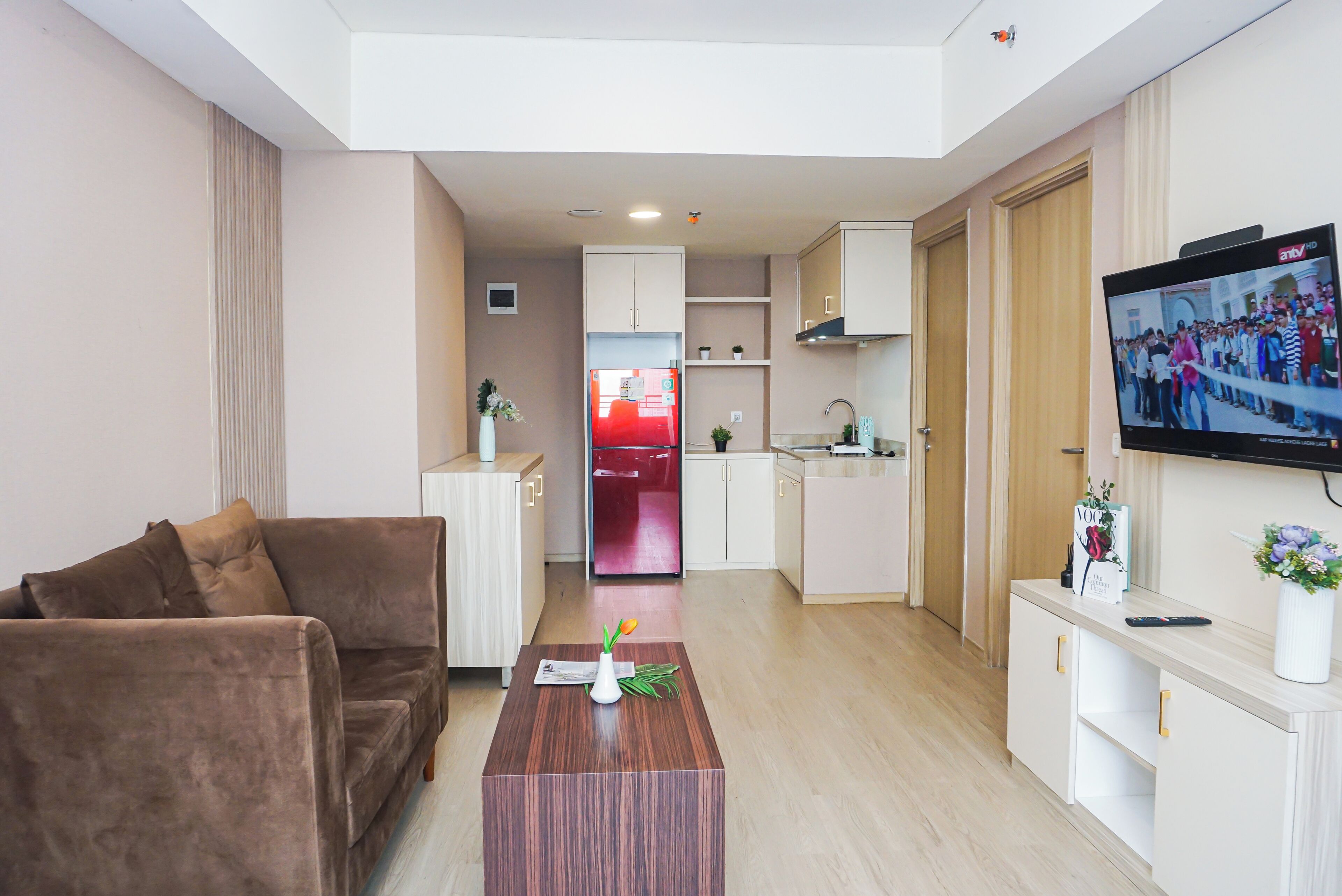 Ein modernes Wohnzimmer mit einem braunen Sofa, einem Holztisch und einem an der Wand befestigten Fernseher.