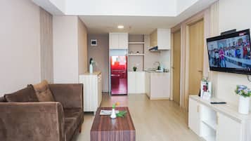 Ein modernes Wohnzimmer mit einem braunen Sofa, einem Holztisch und einem an der Wand befestigten Fernseher.