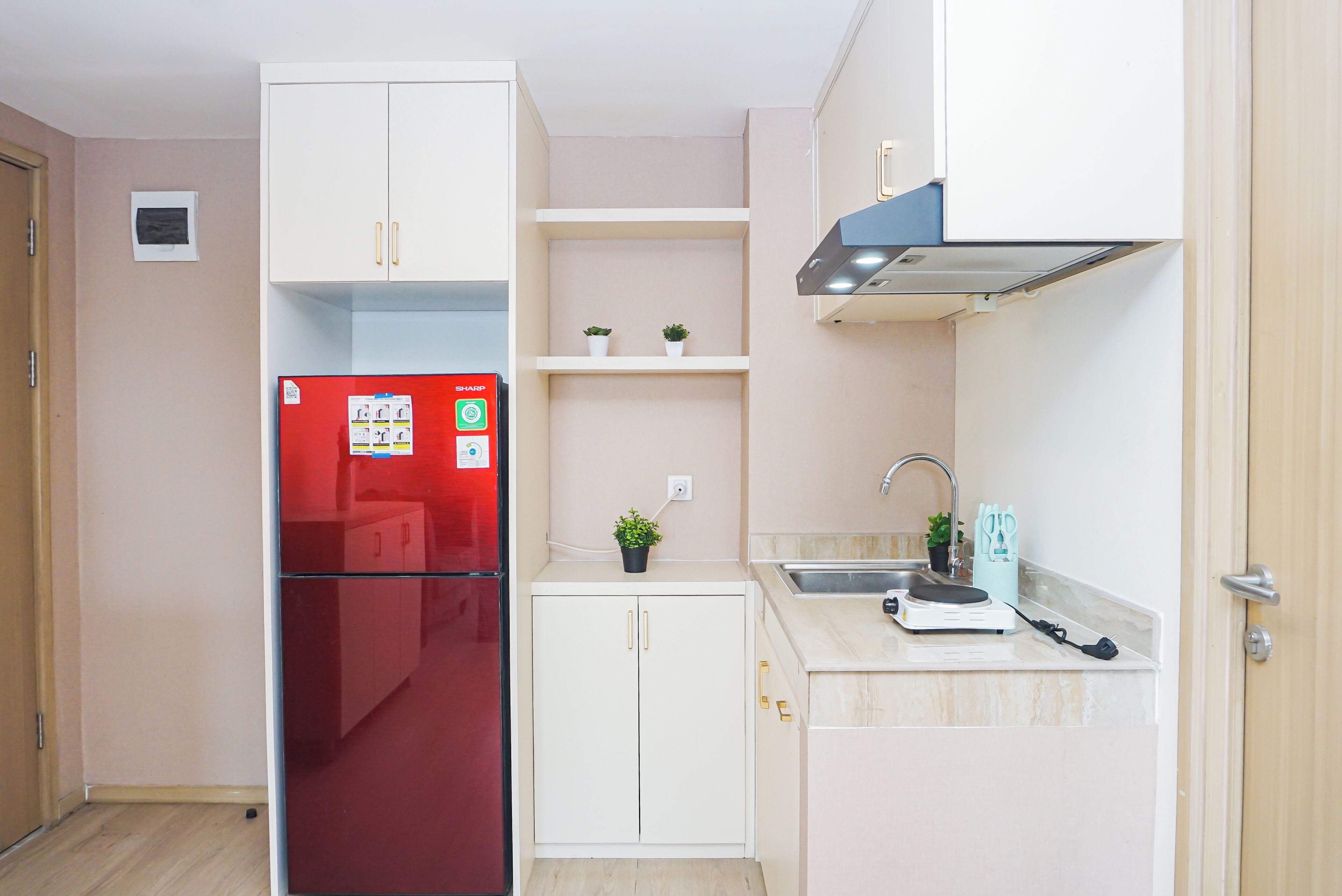 Eine kleine Küche mit einem roten Kühlschrank, weißen Schränken, einer Spüle und einer Arbeitsplatte.