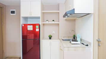 Eine kleine Küche mit einem roten Kühlschrank, weißen Schränken, einer Spüle und einer Arbeitsplatte.