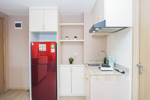 Eine kleine Küche mit einem roten Kühlschrank, weißen Schränken, einer Spüle und einer Arbeitsplatte.