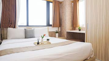 Ein Hotelzimmer mit einem großen Bett, einem Nachttisch, einer kleinen Pflanze und Blick auf die Stadt.