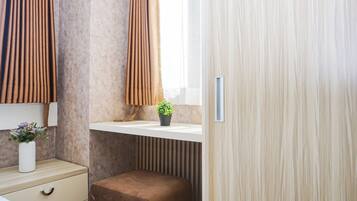 Ein Schlafzimmer mit einem Bett, einem Nachttisch, einem Fenster mit Vorhängen und einer Wandablage mit einer Pflanze.