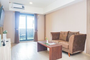 Ein modernes Wohnzimmer mit einem braunen Sofa, einem Holztisch und einem großen Fenster mit Vorhängen.