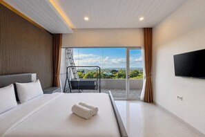 Ein modernes Hotelzimmer mit einem großen Bett, einem Balkon mit Blick und einem angebrachten Fernseher, sowie einer Schiebetür.