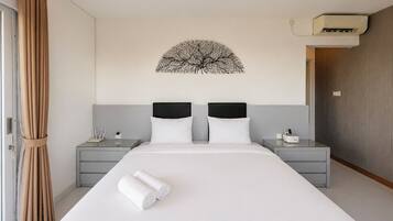 A hotel room with a large bed, two bedside tables, a wall-mounted air conditioning unit, and a curtain on the left.