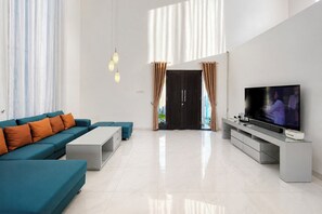 A modern living room with a sofa, coffee table, TV, and a door leading to another room.