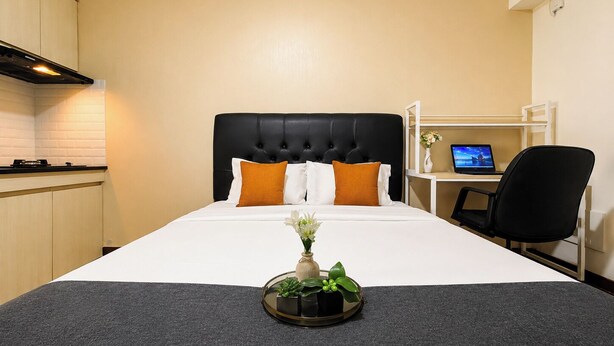 Ett hotellrum med en säng, ett skrivbord med en dator och ett litet kök.