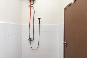 Eine Dusche mit Handbrause und Wandarmatur, verbunden durch rote und graue Schläuche.