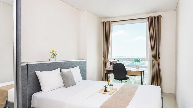 Een hotelkamer met een bed, een bureau en een raam met gordijnen.