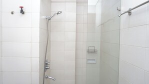 Een douche met een handdouche, een wandmengkraan en een douchecabine met glazen wanden.